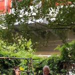 Kolja Nixdorf liest, Oda Sajouz sitzt neben ihm und auf der Hochtrasse fährt ein Regionalzug vorbei