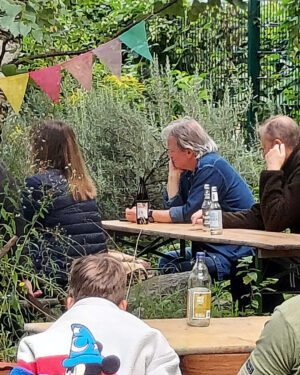Im Garten sitzen mehrere Personen und hören konzentriert der Lesung zu.
