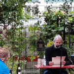 Kolja Nixdorf sitzt im Garten der Kulturfabrik Moabit und liest eine Geschichte vor